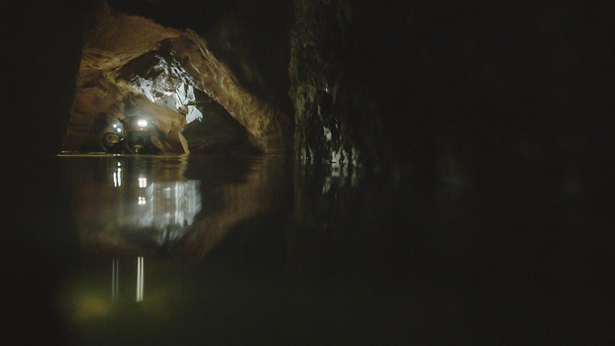 Divers moving through a dark cave together in “The Rescue.” Cr: National Geographic